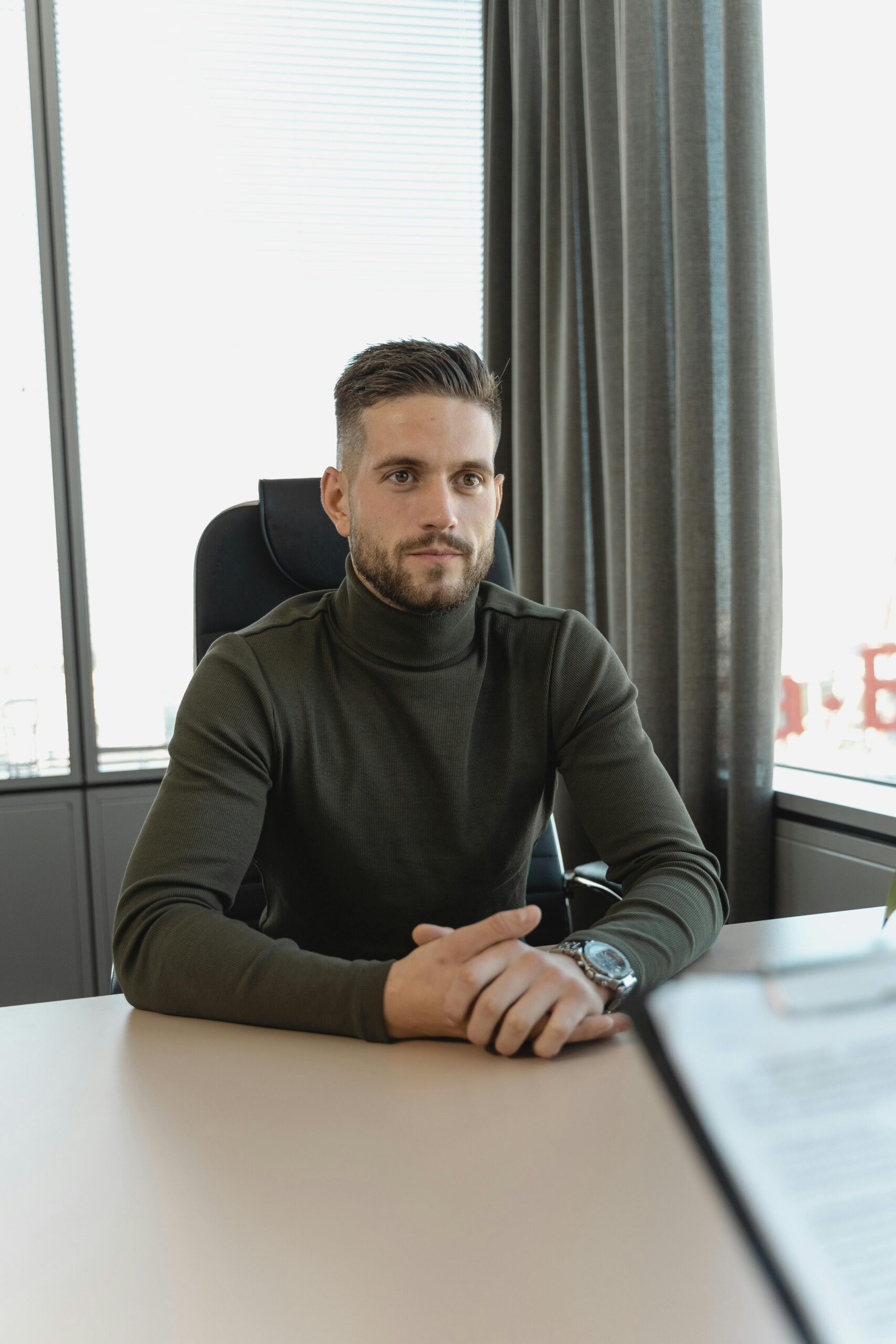 Businessman with a thoughtful expression sitting at a desk in a modern office.